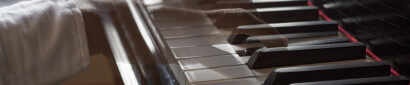 A close-up, cropped image of a dark-skinned hand playing a piano. It is semi-transparent, showing the movement of the hand.