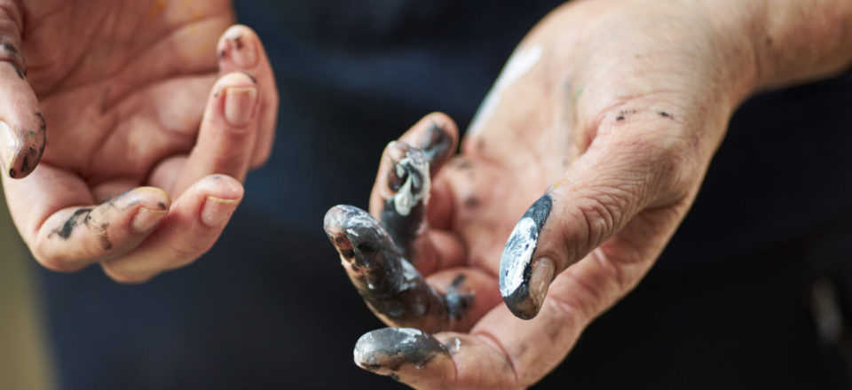 Close up of two white hands, both are palm up and in a natural pose. Both hands have paint on them.